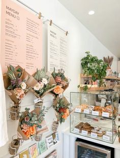 a bakery with flowers on the counter and menus hanging from the wall behind it