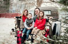 a family sitting in the back of an old pickup truck with christmas decorations on it