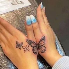 two hands with butterfly tattoos on them