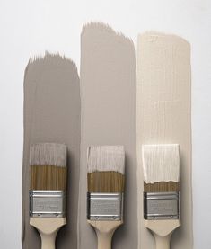 three paintbrushes with different shades of gray and beige on them, one is white