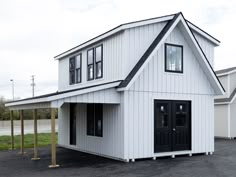 a white house with black doors and windows on the side of it's roof