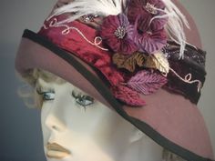 "This luscious mauve felt has been hand made using a vintage hat block. All hand made. Added flowers, feathers and 2 tone velvet band make this hat quite a statement piece. The 2.5\" band that encircles the crown is decorated with gold & lurex swirled trim, & sequins, against mauve and burgundy velvet. White small ostrich feathers, and light and dark purple flowers with wine, purple and green velvet leaves adorn the side in a lush melange. Black grosgrain ribbon trims the edge of brim. A special Handmade Formal Hats, Elegant Burgundy Hat For Winter, Elegant Red Felt Hat For Formal Occasions, Handmade Fitted Hats For Formal Occasions, Handmade Fitted Formal Hats, Formal Fitted Handmade Hats, Vintage Felt Hat For Party In Fall, Vintage Felt Hat For Fall Party, Elegant Fall Cloche Hat