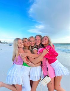 four girls hugging each other on the beach