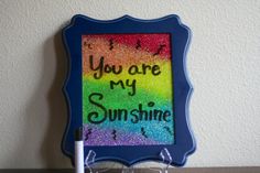 a blue frame with the words you are my sunshine written on it next to two glasses