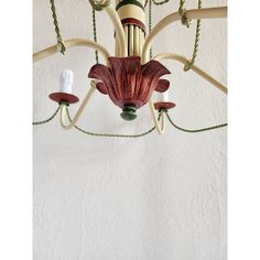 a chandelier with red flowers hanging from it's sides and green cords