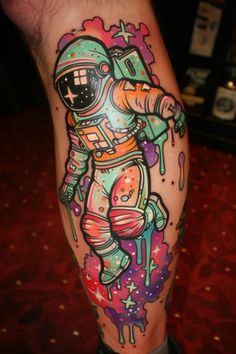 an astronaut tattoo on the leg of a man with colorful paint splattered all over it