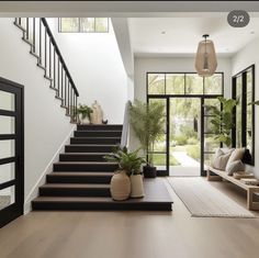 a staircase leading up to the second floor in a modern home with potted plants on either side