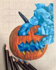 a drawing of a pumpkin with blue and orange paint on it, surrounded by crayons