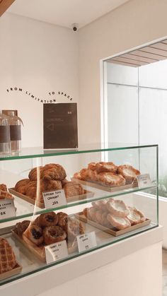 a display case filled with lots of different types of pastries on top of glass shelves