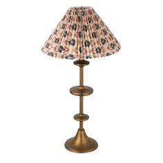 a lamp that is sitting on top of a metal stand with a fabric shade over it