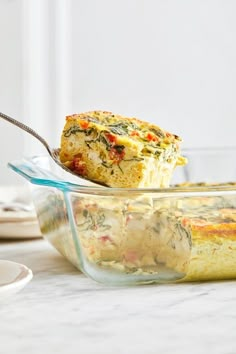 a glass casserole dish with a piece of quiche in it and a fork