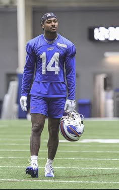 a football player is walking on the field with his helmet and glove in one hand