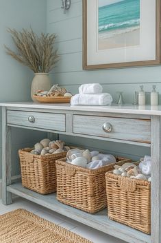 two wicker baskets under a console table with towels and other items on it in a coastal style bathroom