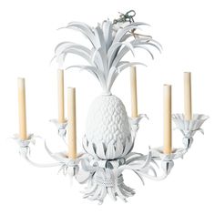 a white pineapple chandelier with five candles in the center and an insect on top