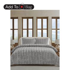 a bed in a room with two windows and a gray comforter on top of it