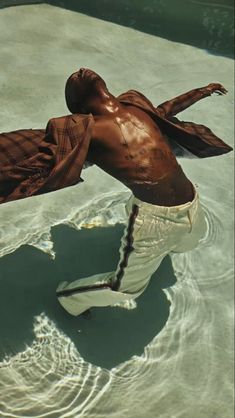 a man is standing in the water with his arms spread out and legs bent back