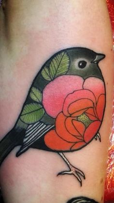 a small bird with flowers on it's back leg, sitting next to a red rose