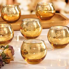 gold colored glass bowls on a tray with flowers in the middle and one bowl filled with water