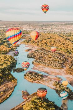 several hot air balloons flying over a river