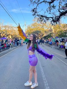 a woman in a purple costume is standing on the street