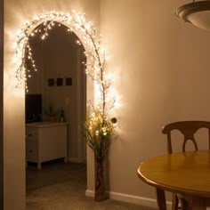 a dining room table with a potted plant and lights on the wall behind it