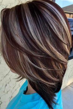 the back of a woman's head with dark brown hair and highlights on it