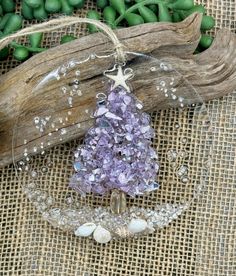 a purple christmas tree ornament sitting on top of a piece of drift wood