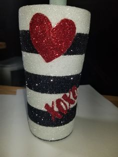 a cup that has been decorated with glitter and a red heart on the side, sitting on a table