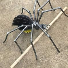 a metal spider sitting on top of a wooden stick