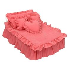 a baby bed with pink ruffled sheets and pillows on it's side, in front of a white background