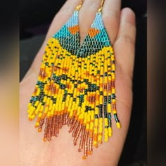 a woman's hand holding a yellow and blue beaded necklace with fringes