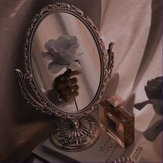 a mirror sitting on top of a table next to a stack of books and a flower