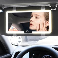 a woman is looking at her reflection in the mirror as she sits in a car