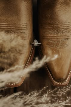 a pair of brown boots sitting on top of a fur covered floor next to a white feather