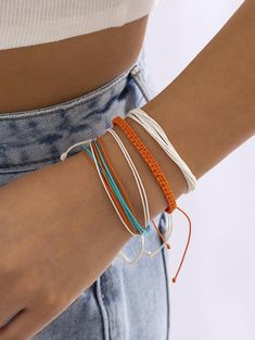 a close up of a person wearing three bracelets on their wrist and one with an orange string