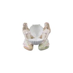 two figurines sitting on top of a white bowl with a shell in it