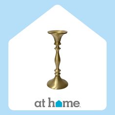 a gold candle holder sitting on top of a blue and white sign that says at home