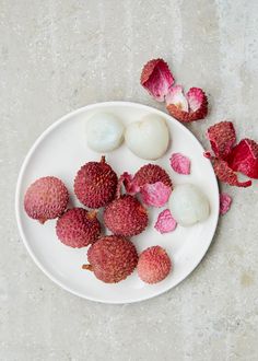 a white plate topped with different types of fruits and veggies next to flowers