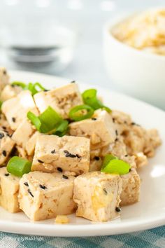 tofu with sesame seeds and green onions on a white plate