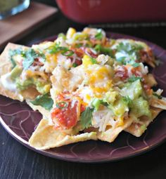 nachos with cheese, tomatoes and avocado are served on a plate