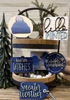 some wooden signs that are sitting on a table with pine trees in the back ground