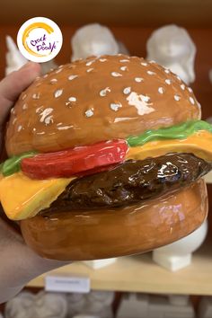 a hand holding a fake hamburger made out of plastic