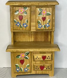 a wooden cabinet with flowers and hearts painted on it