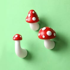 three red and white mushrooms sitting on top of a green surface