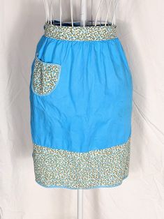 a blue skirt is hanging on a clothes rack with white pins in the pocket and an orange flowered shirt underneath it