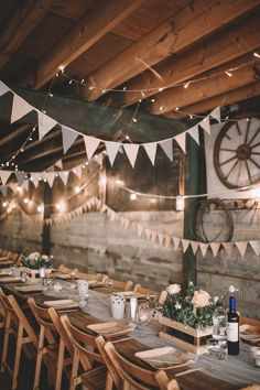 a long table with wooden chairs and white bunting hanging from it's ceiling