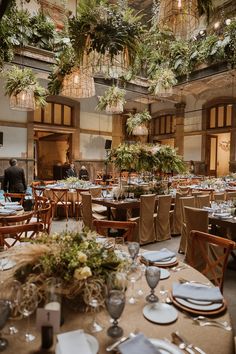 an indoor dining area with tables and chairs, plants hanging from the ceiling above them