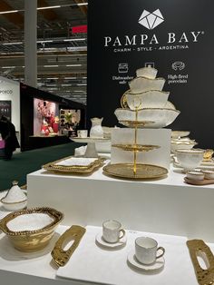 a table topped with lots of white and gold dishes next to a sign that says pampa bay