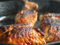 three pieces of chicken cooking in a frying pan