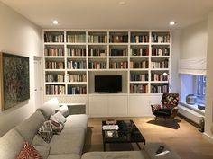 a living room filled with lots of furniture and bookshelves covered in bookcases